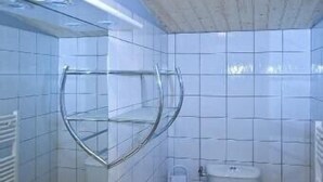 Un bany amb un lavabo blanc, un mirall i un vàter.