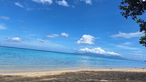 Une plage avec une eau d’un bleu limpide et un rivage sablonneux.