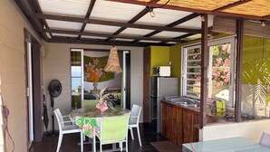 Une pièce comprenant une table à manger, des chaises, un ventilateur, un four à micro-ondes et un réfrigérateur.