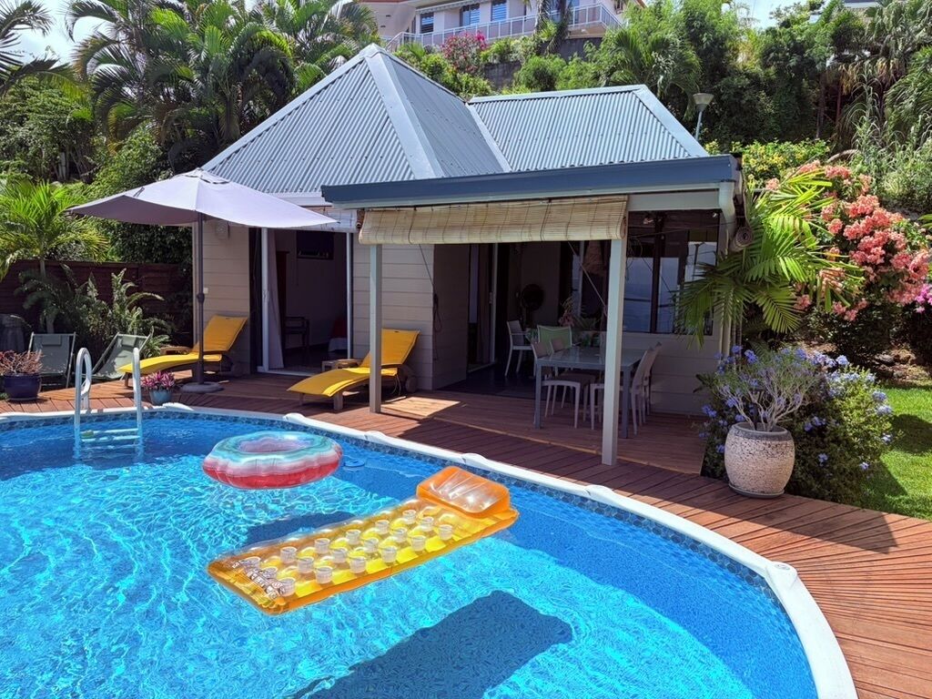 Une piscine avec des bouées gonflables, un patio couvert et un bâtiment doté d’un toit en pente.