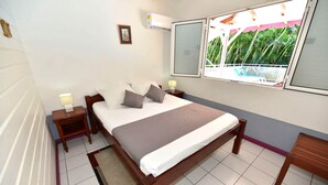 Una camera da letto con un letto, comodini, una finestra vista balcone e un condizionatore d'aria.