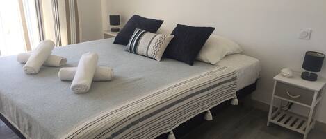 A neatly made bed with rolled towels, a striped blanket, and two bedside tables with lamps and decorative items.