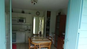Una cocina compacta con una mesa y sillas, un microondas y un reloj en la pared.
