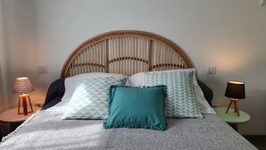 A bed with a woven headboard, two patterned pillows, a teal throw, and two bedside lamps on small tables. - Quiet village, panoramic view, Scandola reserve, warm river Le Fango (Galéria)