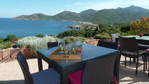 A table with chairs and a tray of bottles, overlooking a coastal landscape with mountains. - Quiet village, panoramic view, Scandola reserve, warm river Le Fango (Galéria)
