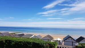 A coastal view with a beach, clear sky, and solar panels on buildings.