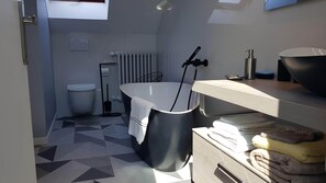 Ein modernes Badezimmer mit einer freistehenden Badewanne, einer Toilette und einem Waschbecken mit gestapelten Handtüchern.