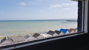 A view of a beach with several beach huts and a pier in the distance.