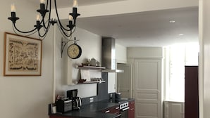 Una cocina moderna con una isla central, una araña y un reloj en la pared.