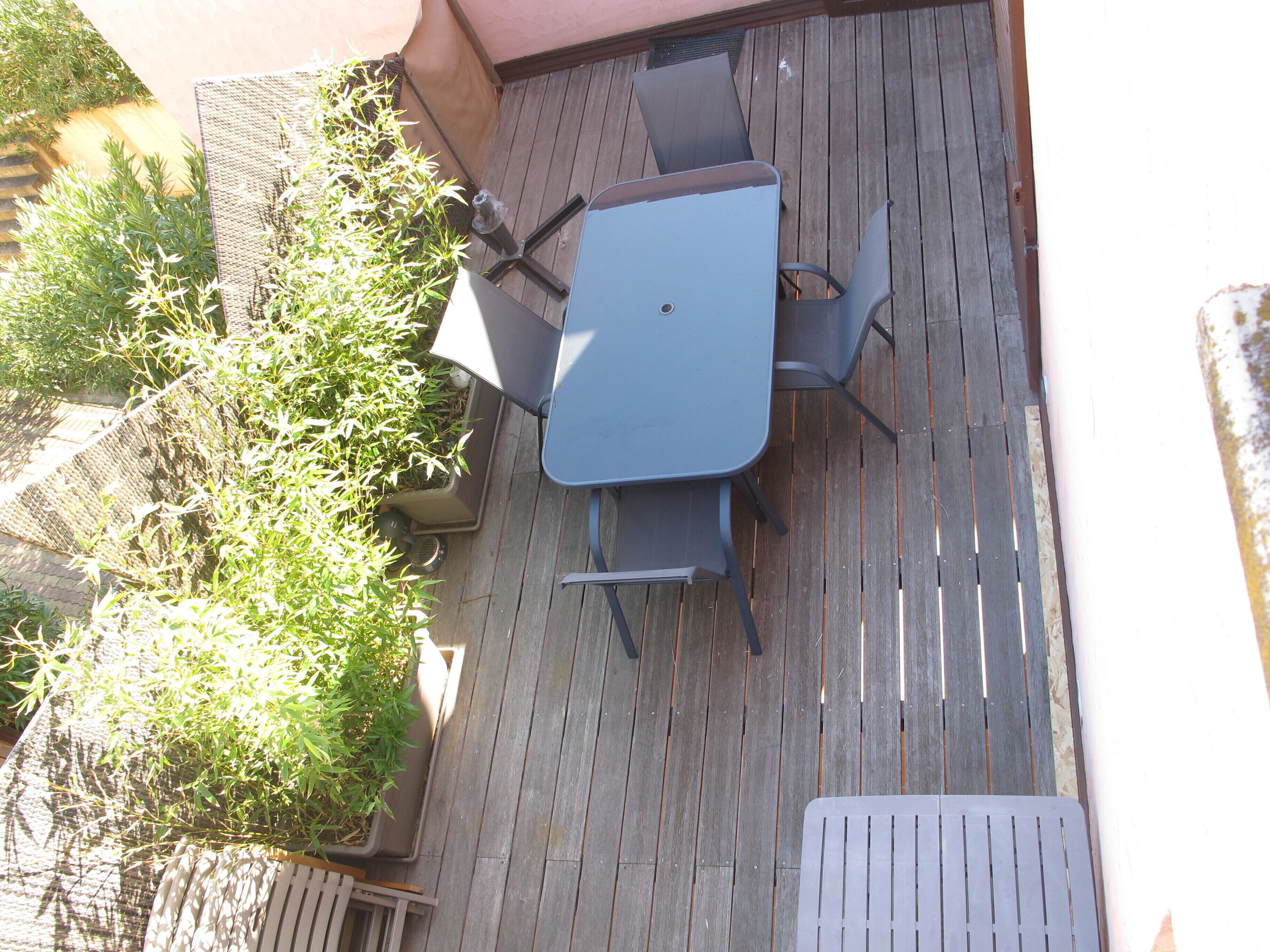 A patio with a table and chairs, surrounded by potted plants.