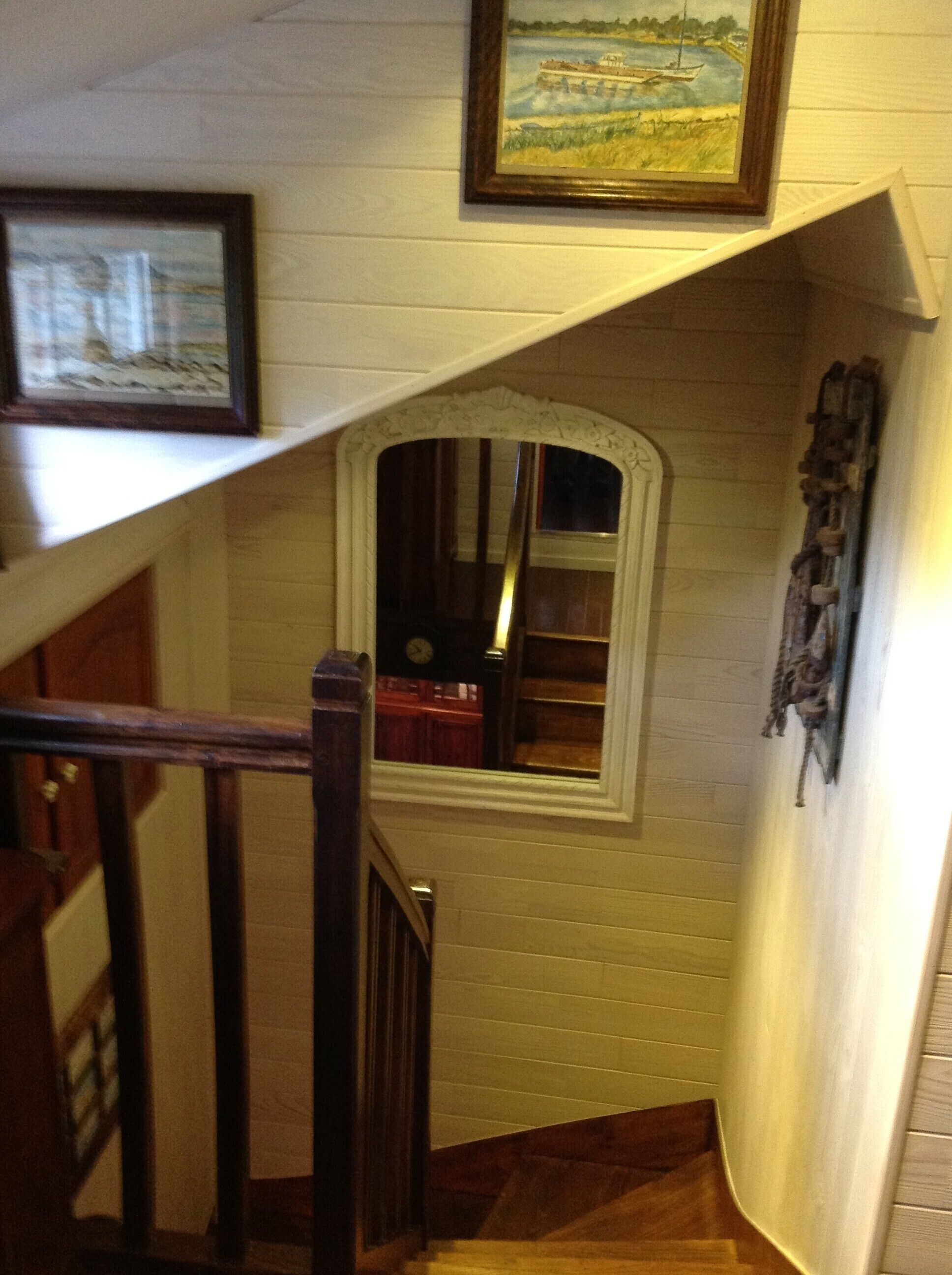 Eine Treppe mit Holzgeländer, einem kleinen Fenster und einem gerahmten Gemälde darüber.