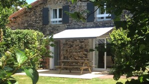Una casa de piedra con un porche cubierto y una mesa de madera.