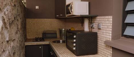 A compact kitchen with a microwave, toaster, and sink.