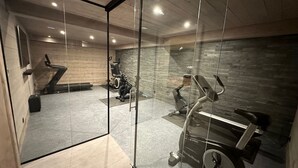 Een moderne sportschoolruimte met trainingsapparatuur, een trap en een stenen muur.