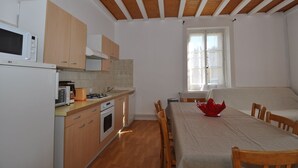 A compact kitchen with wooden cabinets, a microwave, an oven, and a dining area with a table and chairs. - Apartment Prémanon town center 6p (Prémanon)