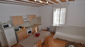 A compact kitchen with wooden cabinets, a dining table, and a sofa. - Apartment Prémanon town center 6p (Prémanon)