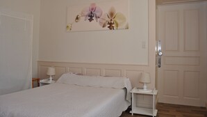 A bedroom with a bed, two bedside tables with lamps, a door, and a wall-mounted floral artwork. - Apartment Prémanon town center 6p (Prémanon)
