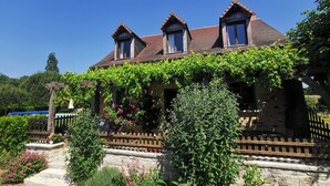 A traditional house with a stone facade, a wooden porch, and a garden with various plants and flowers. - Haven of peace, sweet home, swimming pool, 7 beds between Tours and Poitiers (Senillé-Saint-Sauveur)
