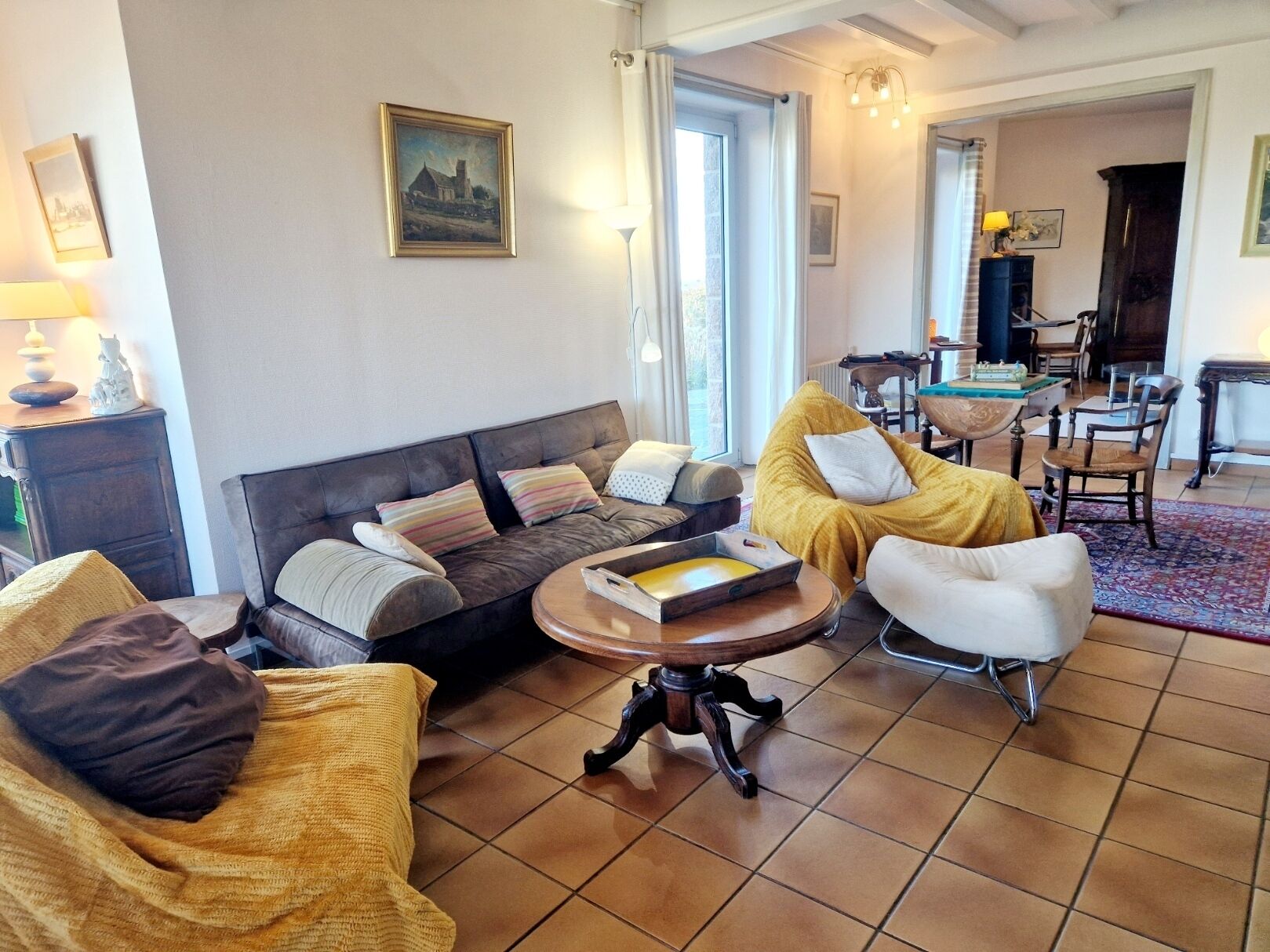 En stue med sofa, lænestole, sofabord og et billede på væggen.