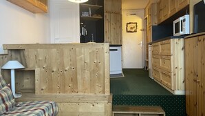 A compact kitchen with wooden cabinets, a microwave, and a refrigerator. - Avoriaz center, Large  Studio on two levels:rented from Saturday to Saturday  (Morzine)