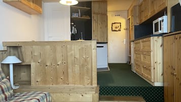 Une cuisine de taille réduite, dotée de meubles en bois, d’un four à micro-ondes et d’un réfrigérateur.