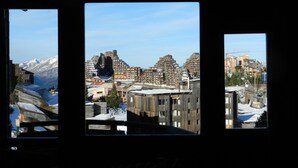 A view through three windows of a cityscape with modern buildings, a mountain in the background, and a construction crane. - Avoriaz center, Large  Studio on two levels:rented from Saturday to Saturday  (Morzine)