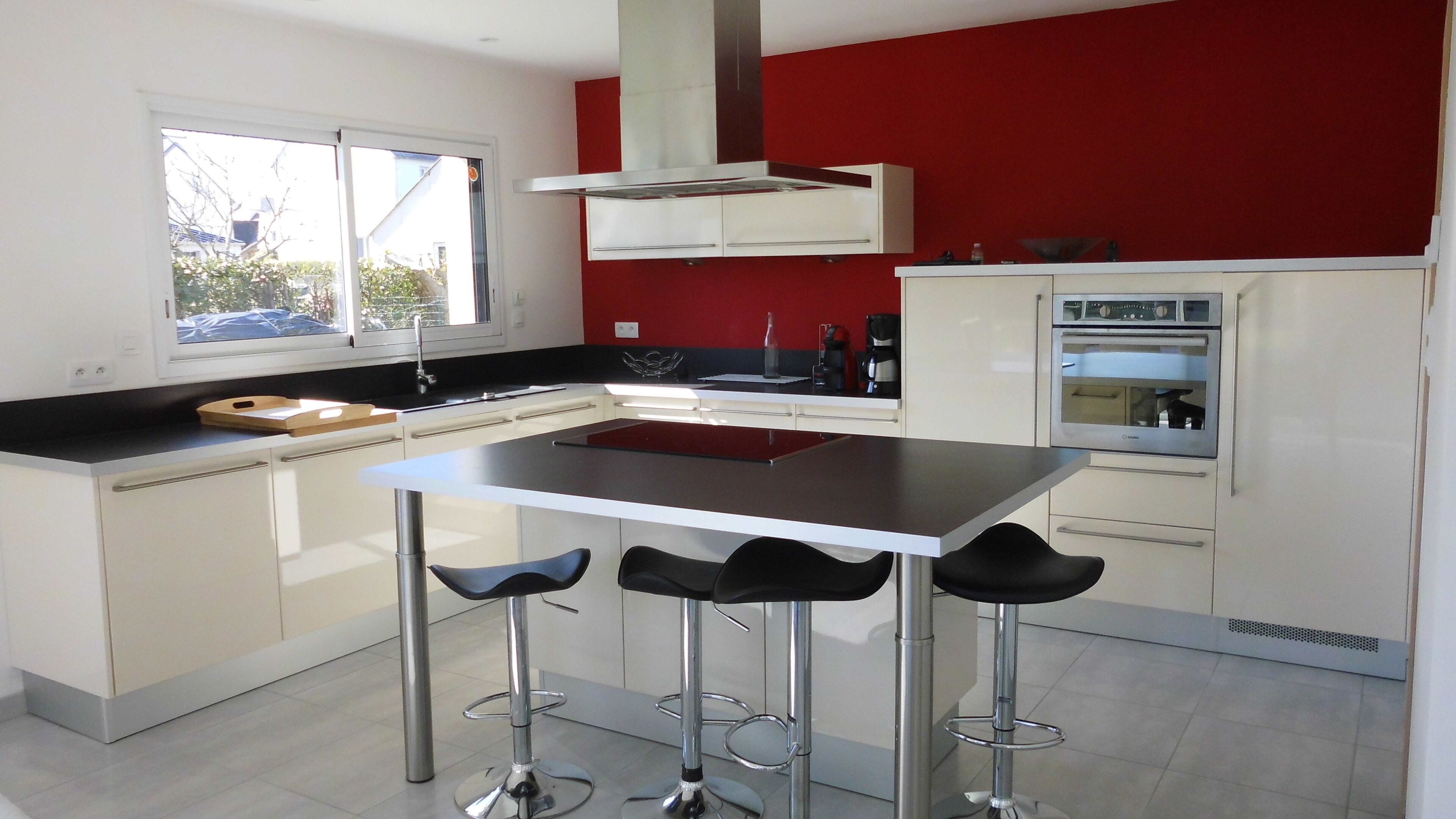 A modern kitchen with a central island, bar stools, a built-in oven, and a window with a view of the outside.