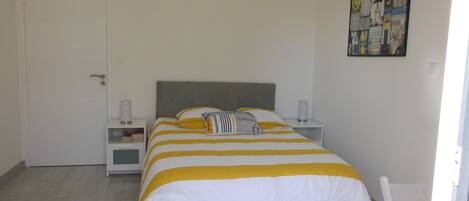 A bedroom with a bed, two bedside tables, a door, and a wall art piece.