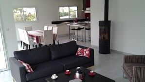 Un salon moderne avec un canapé noir, une table basse et un coin cuisine à l’arrière-plan.