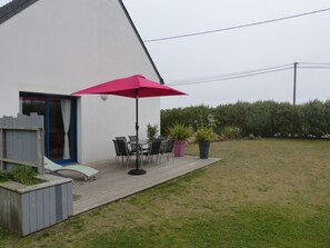 A patio with a table and chairs, a red umbrella, and potted plants. - 3-star seaside villa, sleeps 7, 150 m from the beach and the GR34 trail. Large, enclosed garden (Plounéour-Brignogan-Plages)