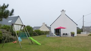 A backyard with a swing set, a slide, and a patio area with outdoor furniture. - 3-star seaside villa, sleeps 7, 150 m from the beach and the GR34 trail. Large, enclosed garden (Plounéour-Brignogan-Plages)