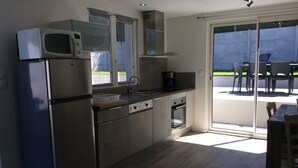 A modern kitchen with stainless steel appliances, a built-in oven, and a large sliding glass door leading to an outdoor patio area.