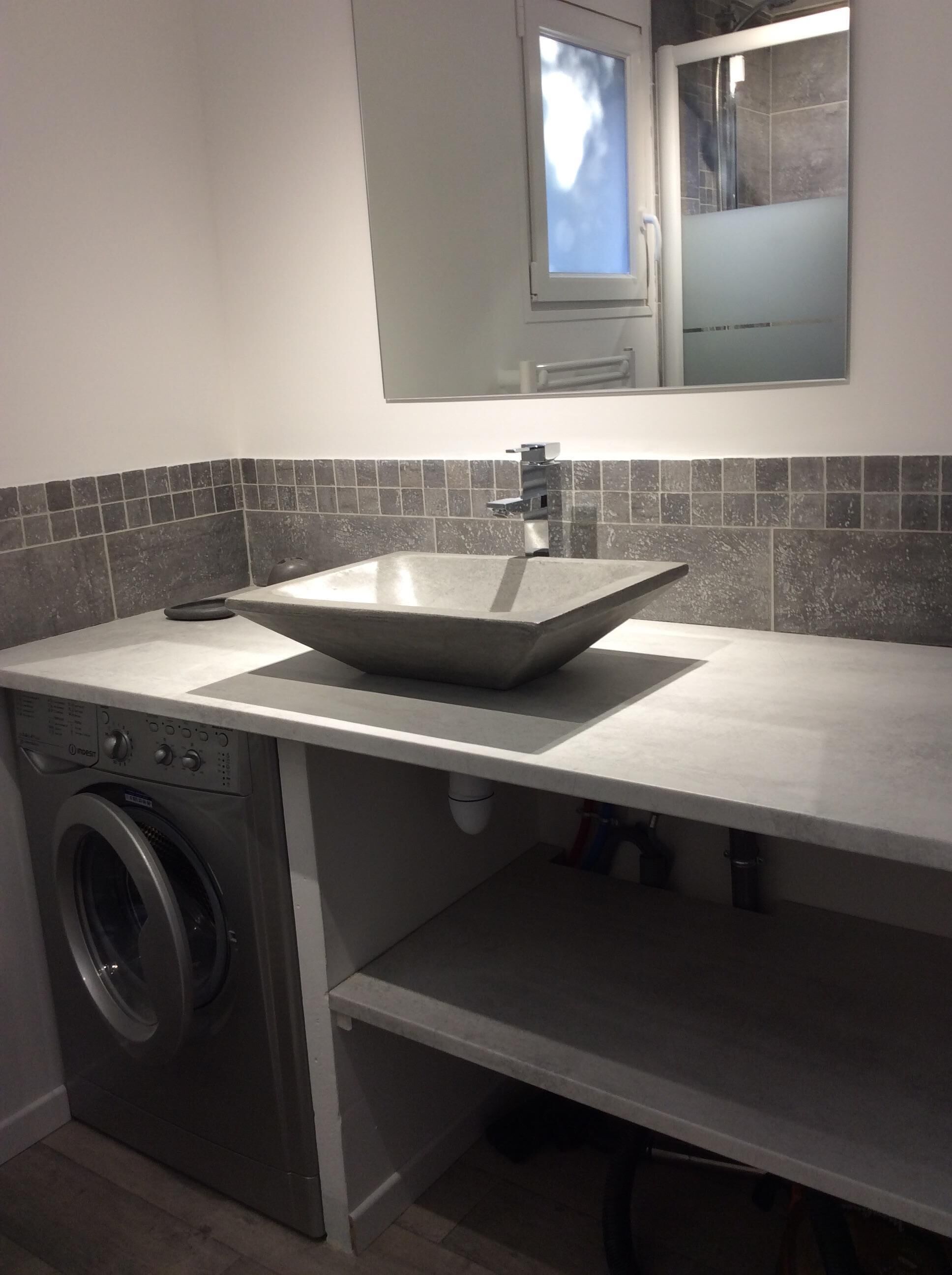 Une cuisine compacte dotée d’un évier encastré, d’un lave-linge et d’un miroir au-dessus du plan de travail.