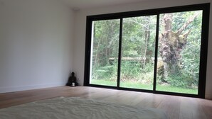A bedroom with a large window, wooden flooring, and a bed. - The forest, 400 m from an arm of the sea.  (Carnac)