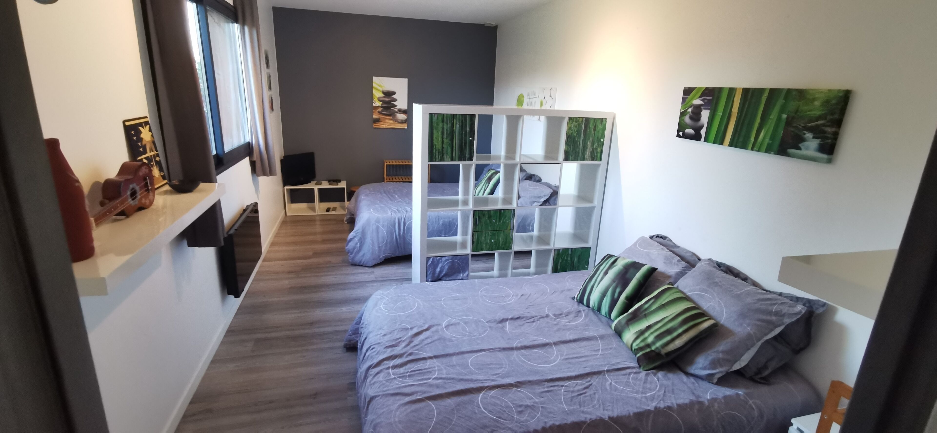 Une chambre à coucher avec un lit, un meuble de rangement blanc, une télévision et des œuvres d’art accrochées aux murs.