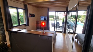 A bedroom with a large window, a desk with a lamp, and a view of the outdoor area. - Vacation villa with swimming pool near Orient lakes in Champagne (Villa Temple) (Lesmont)