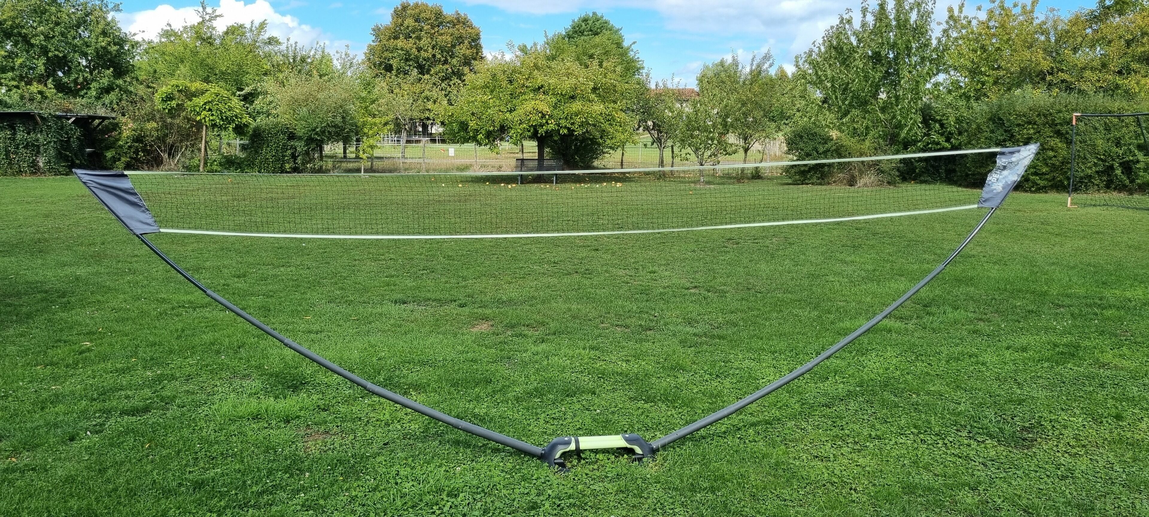 A netted area on a grassy field with a pole structure in the foreground.