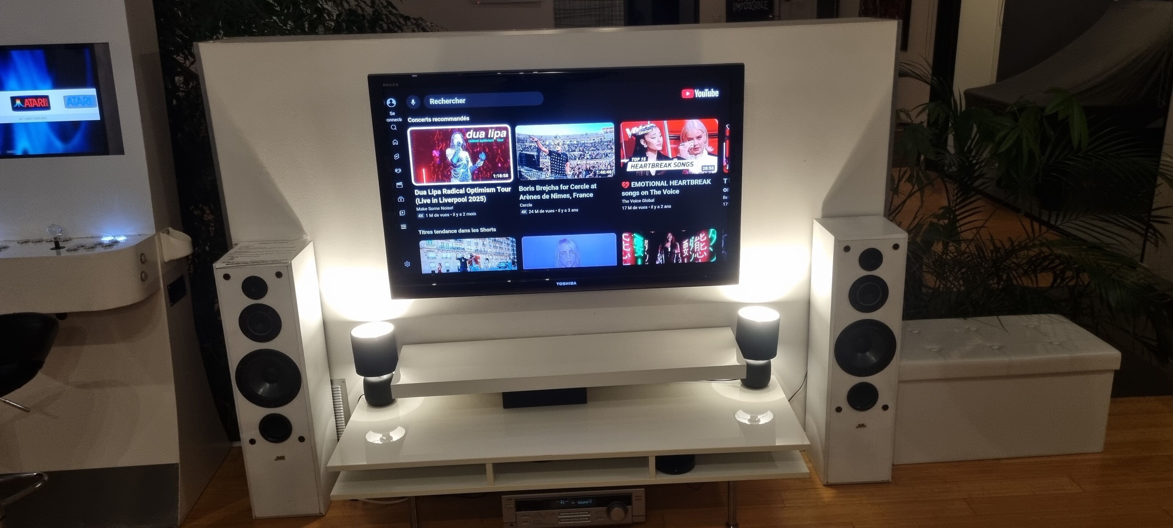 A flat-screen TV mounted on a white stand with two speakers on either side.