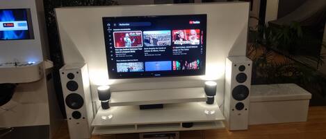 A flat-screen TV mounted on a white stand with two speakers on either side.