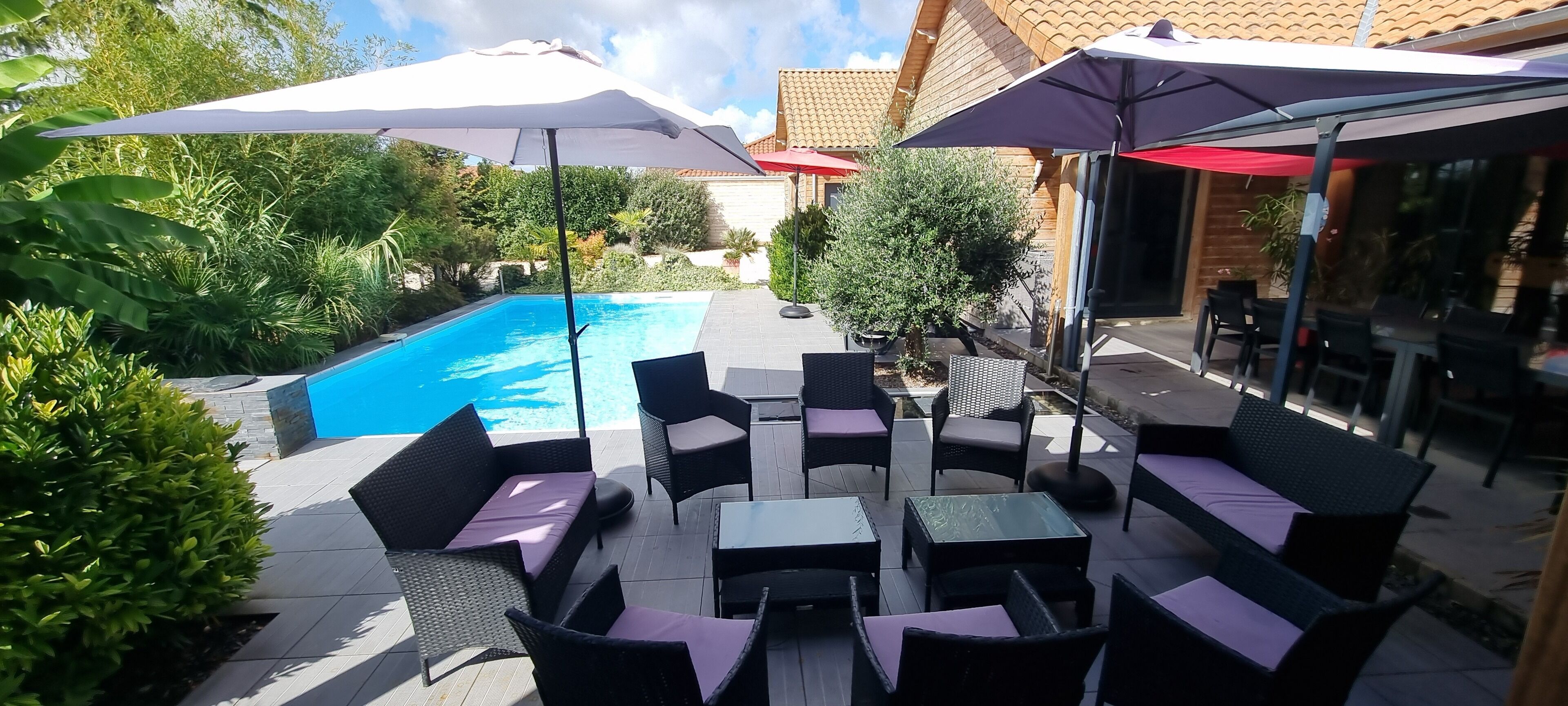 Un patio exterior con piscina, mobiliario y sombrillas.