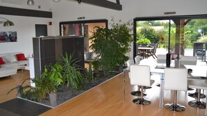 Ein modernes Interieur mit Holzboden, weißen Sofas, einer Glastrennwand und einem Essbereich mit weißen Stühlen.