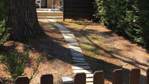 A wooden fence with a sign reading "L3" leading to a building with a tiled roof and a covered outdoor seating area. - Cottage in the heart of the pines (Lacanau Océan)