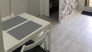A room with a white table, a chair, a wardrobe, and a door leading to a closet with a patterned wall. - Cottage in the heart of the pines (Lacanau Océan)