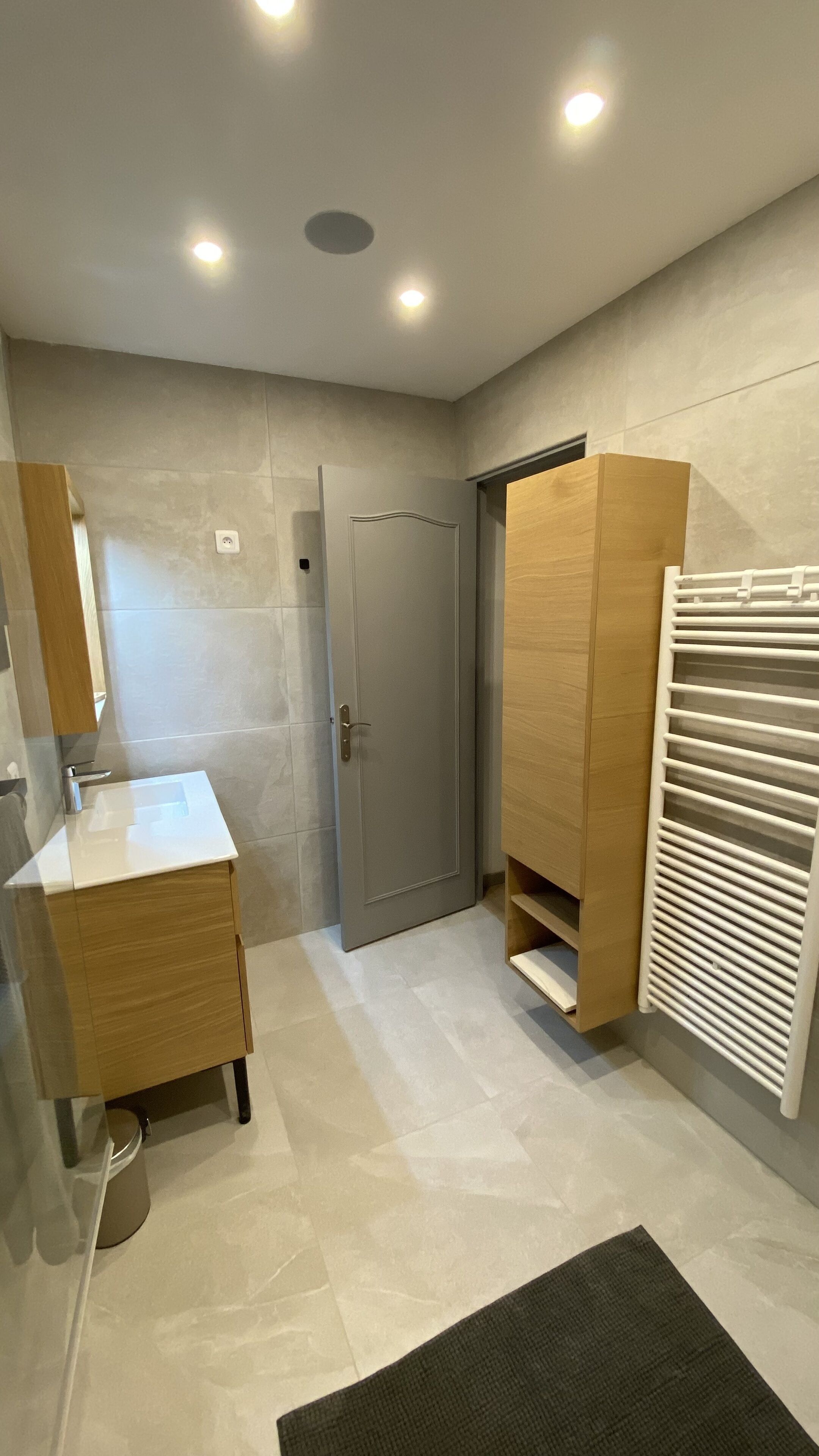 Un baño moderno con tocador de madera, un espejo, un perchero y una puerta.