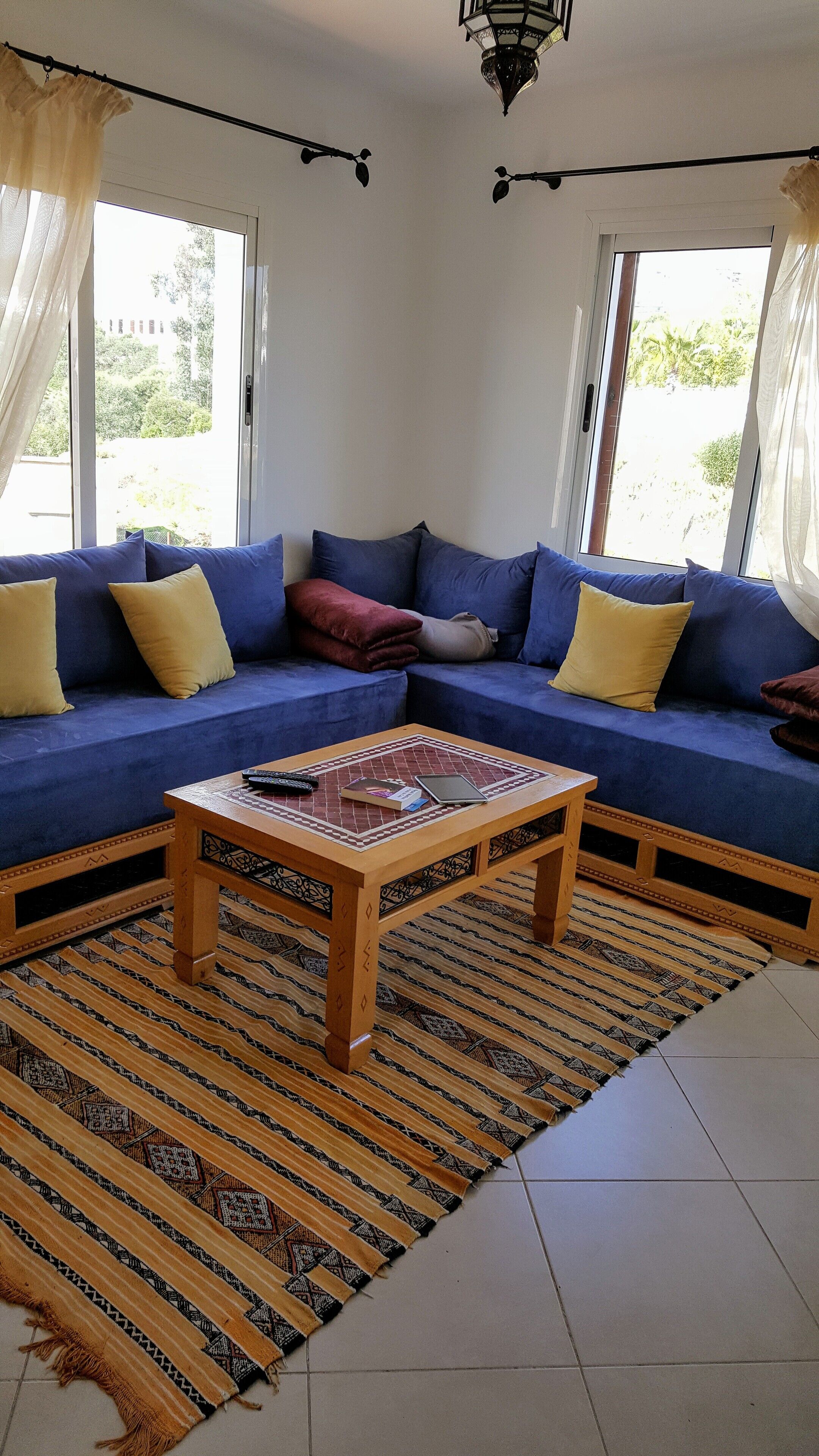 A living room with a blue sofa set, a wooden coffee table, and a patterned rug.