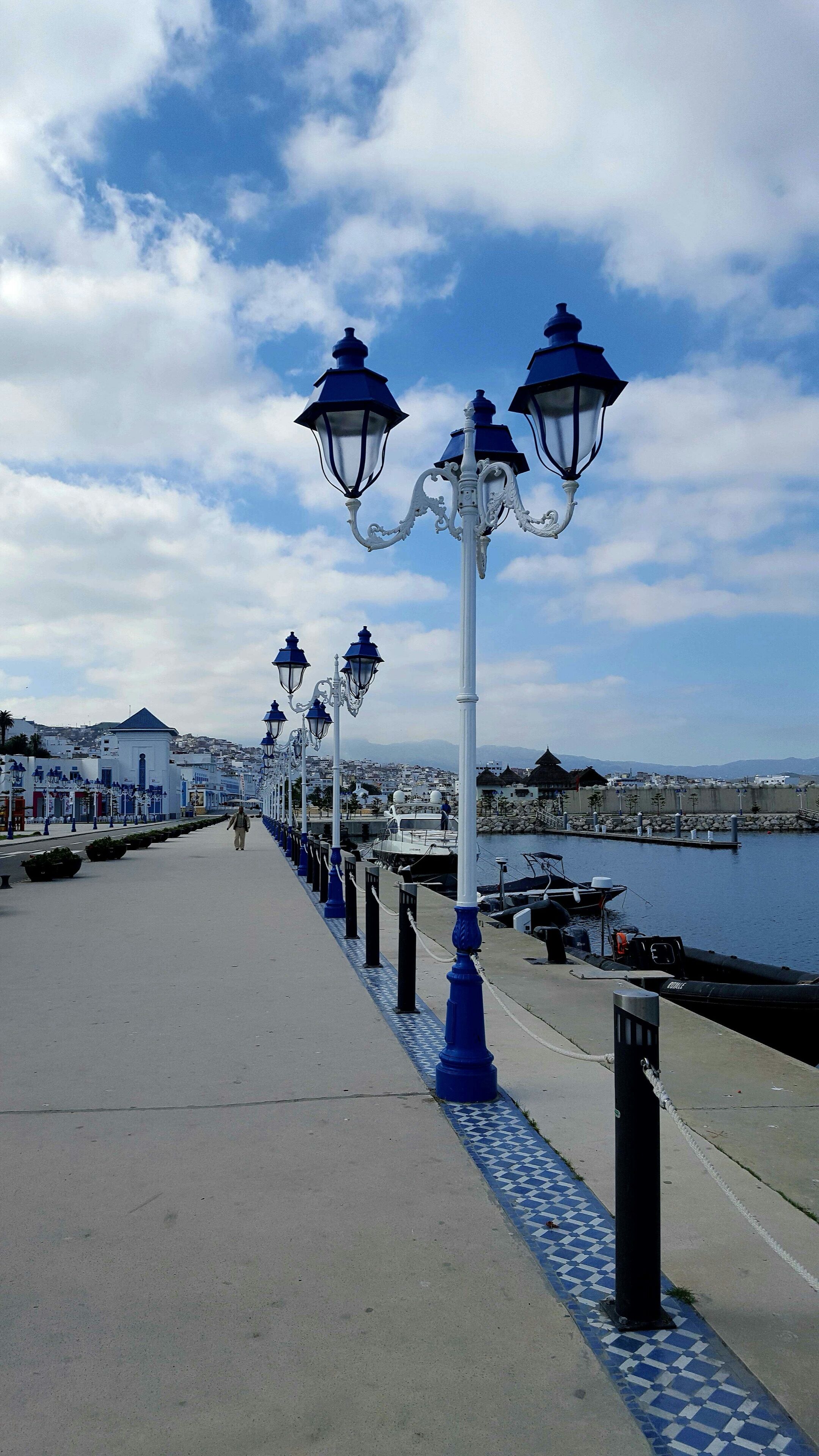 A coastal promenade with ornate street lamps and a view of the sea.