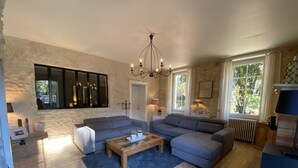 A spacious living room with a large grey sectional sofa, a wooden coffee table, and a chandelier.