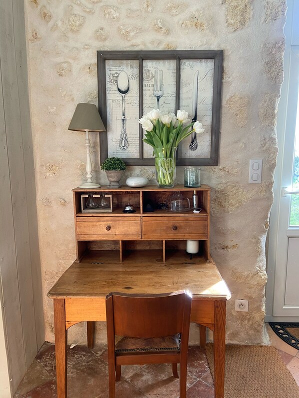 Una mesa de comedor de madera con una silla, un jarrón de flores blancas, una lámpara y un adorno en la pared.