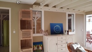 Una habitación con un armario de madera, un cuadro y una silla de mimbre.