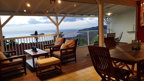Un área de estar al aire libre cubierta con muebles de madera y vista al océano.
